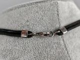 a close up of a black leather choke with a silver clasp