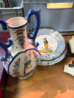 a blue and white vase sitting on a table next to a stack of plates