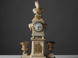 une horloge sur laquelle trône une statue, posée sur une table