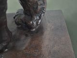 a bronze statue of a dog with a paw on it ' s foot