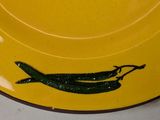 a yellow plate with a green chili on it