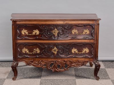 une commode ancienne posée sur un sol à damier, avec un mur en arrière-plan