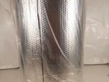 un rouleau de papier d'aluminium emballé dans du film plastique, posé sur un plan de travail