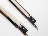 two wooden cues with black and white handles on a white surface