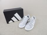 une paire de baskets Adidas blanches devant une boîte noire
