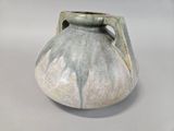 a small vase with a handle on a white table