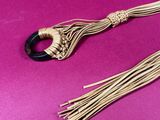 a close up of a gold and black necklace on a pink background