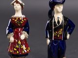 two figurines of people dressed in traditional clothing standing next to each other