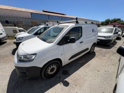 La camionnette blanche est garée sur le parking, à côté d'autres véhicules.