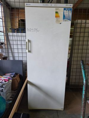 a white refrigerator in a room with a lot of stuff on the floor