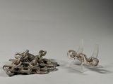 two pieces of silver jewelry sitting on a white surface
