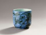 a blue cup sitting on a table with a shadow on the ground