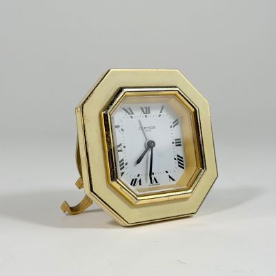 une petite horloge en or avec des chiffres romains