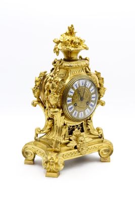 une horloge en or posée sur une surface blanche