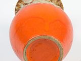 an orange vase that is sitting on a white surface