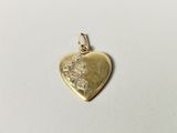 a close up of a gold heart charm on a white surface