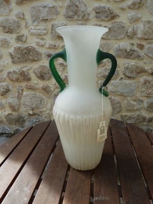 a white vase with green handles sitting on a wooden table