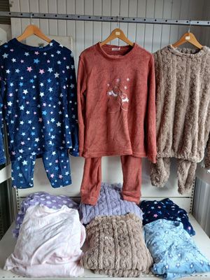 three sets of pajamas hanging on a rack in a room