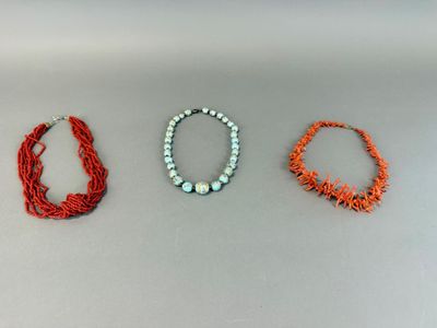 three necklaces of different colors and sizes on a white surface