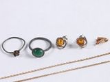 several different rings and necklaces sitting on a white surface