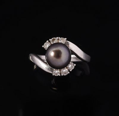 une bague en perle noire et diamants sur fond noir