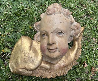 une statue représentant un enfant tenant une pomme, posée sur l'herbe