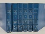 four blue books are stacked on top of each other on a white surface