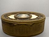 une boîte ancienne en laiton sur laquelle est représentée une femme