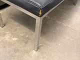 black leather bench with chrome legs in a warehouse area