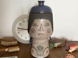 un vase posé sur une table à côté d'une horloge