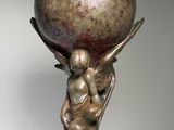 statue of a woman holding a large metal ball on her head