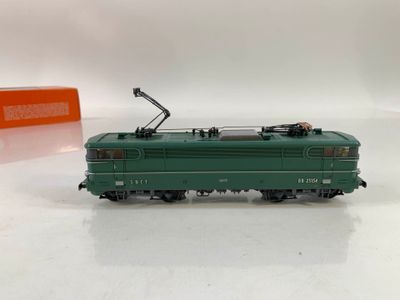Le train vert est sur les rails, à côté d'une pile de cartons orange.