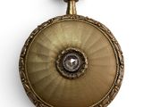 a gold pocket watch with a diamond in the center