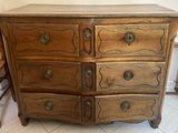 a wooden dresser with four drawers and a chair in front of it