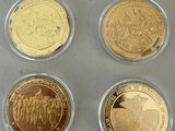 four gold and silver coins in plastic cases sitting on a table