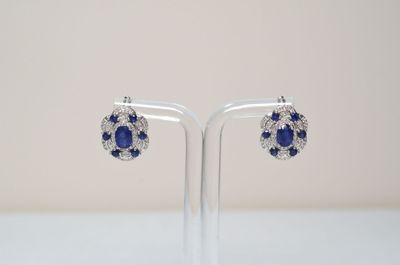 a pair of sapphire and diamond earrings on a clear stand