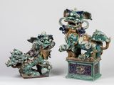 une paire de statuettes « foo foo » bleues et vertes posées sur des socles, sur fond blanc