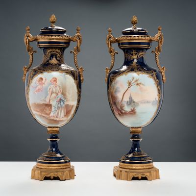une paire de vases anciens ornés de scènes peintes, posés sur une table