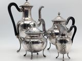 deux théières en argent et une cafetière posées sur un support