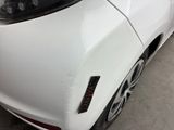 the front end of a white car with a denting dent on it