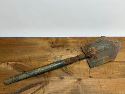 une vieille pelle rouillée posée sur une table en bois