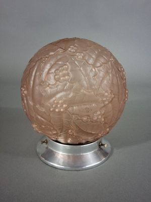 une image représentant une boule de verre rose posée sur un socle en métal