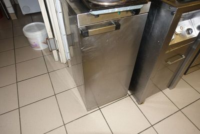 un lave-vaisselle en acier inoxydable posé sur un sol carrelé dans une cuisine
