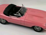 the pink toy car is sitting on a white surface