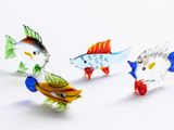 a lot of different colored glass fish on a white surface