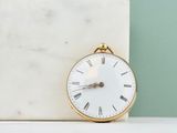 un bloc de marbre blanc sur lequel est posée une horloge dorée