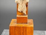 une photo d'une sculpture représentant un ours en peluche assis sur un bloc de bois