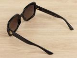 sunglasses on a wooden table with a black frame and brown lens