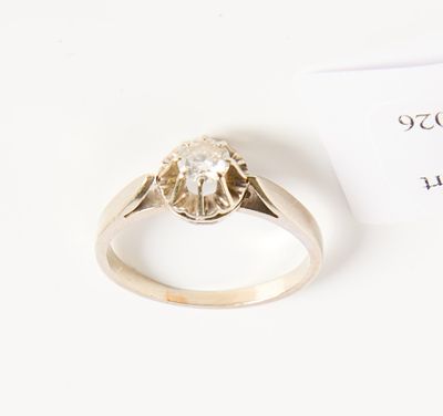 un gros plan d'une bague sertie d'un diamant, posée sur une surface blanche