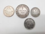 quatre types différents de pièces d'argent sur une surface blanche